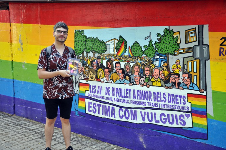 Rubén Serrano davant el mural LGTBI amb el llibre "No estamos tan bien"